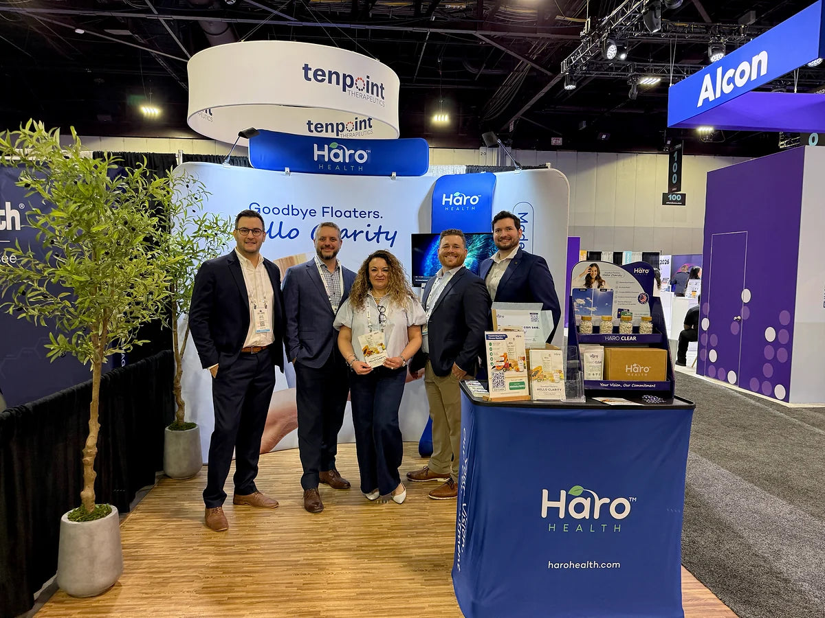 A group gathered beside Haro Health products at a conference booth
