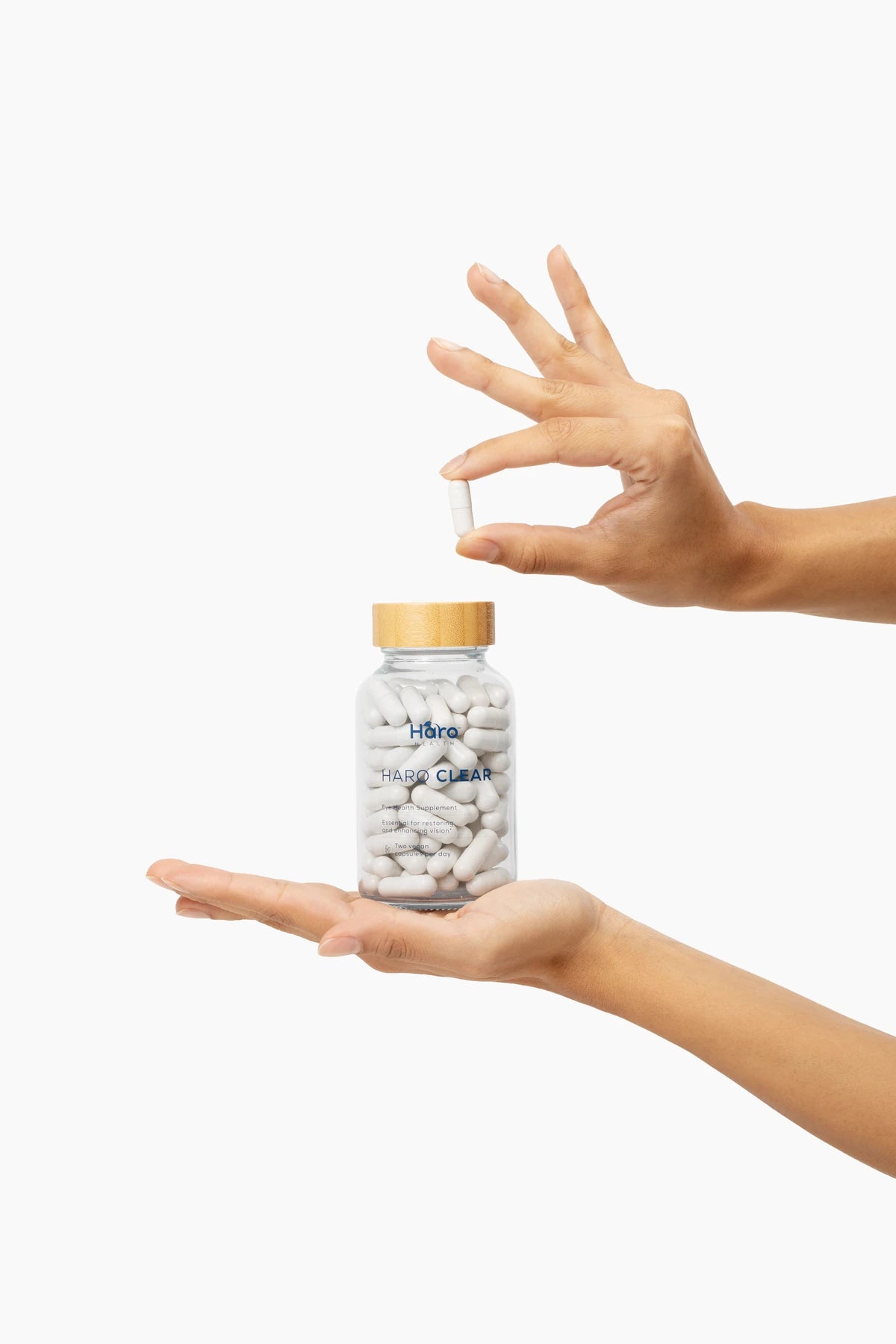 Hands holding a Haro Clear bottle and a single white capsule